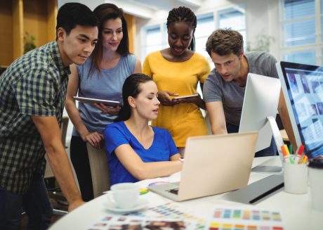 Grupo de pessoas jovens adultas de diferentes etnias olhando para uma tela de computador para simbolizar a ideia de hackathon