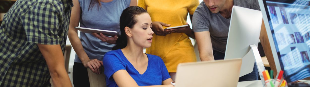 Grupo de pessoas jovens adultas de diferentes etnias olhando para uma tela de computador para simbolizar a ideia de hackathon