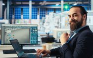 Executivo barbudo sorrindo para câmera enquanto está sentado em uma cadeira em um laboratório. Imagem de capa para o blogpost Obrigação de PD&I da SUFRAMA: como funciona e onde investir