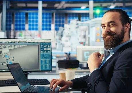 Executivo barbudo sorrindo para câmera enquanto está sentado em uma cadeira em um laboratório. Imagem de capa para o blogpost Obrigação de PD&I da SUFRAMA: como funciona e onde investir