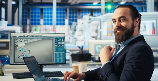 Executivo barbudo sorrindo para câmera enquanto está sentado em uma cadeira em um laboratório. Imagem de capa para o blogpost Obrigação de PD&I da SUFRAMA: como funciona e onde investir