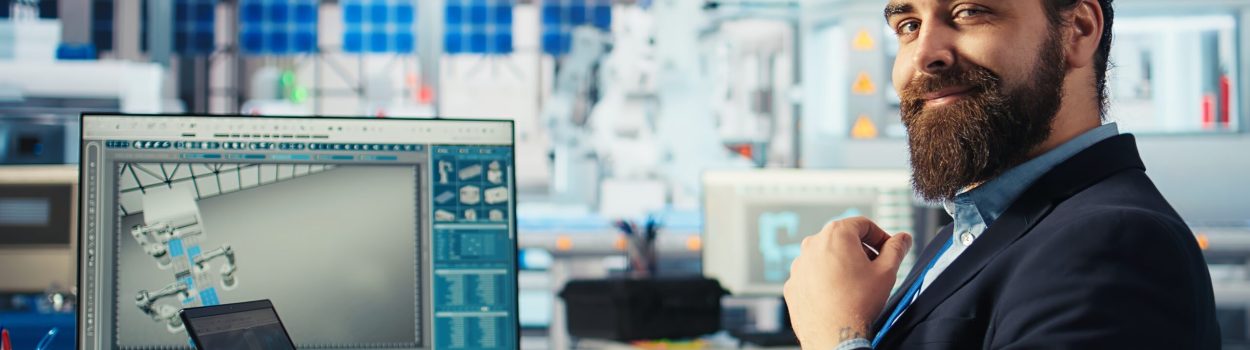 Executivo barbudo sorrindo para câmera enquanto está sentado em uma cadeira em um laboratório. Imagem de capa para o blogpost Obrigação de PD&I da SUFRAMA: como funciona e onde investir